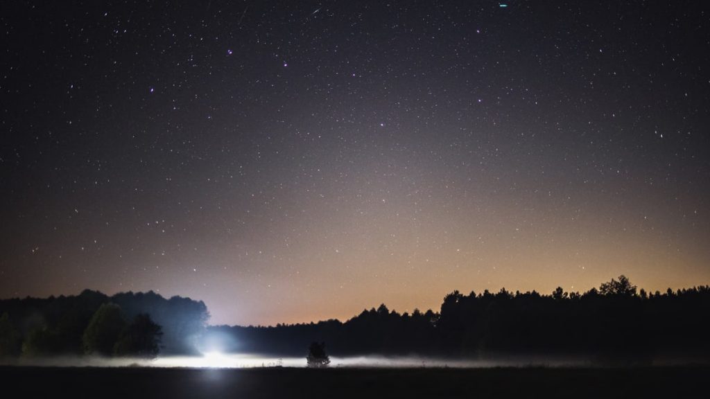 Tranquil night sky view over Polish landscape with stars and distant lights.